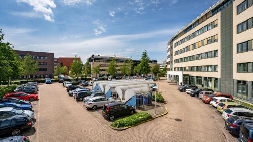 Parkeerruimte bij kantoorpand op Dokter van Deenweg 1, Zwolle, met diverse geparkeerde auto's en omliggende kantoren.