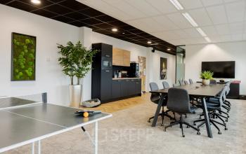 Interieur van een moderne kantoorruimte in Zwolle, Zuiderzeelaan 15-25, met tafeltennistafel, lange vergadertafel en keukenfaciliteiten. Ideaal voor het huren van een veelzijdig en productief kantoorpand.