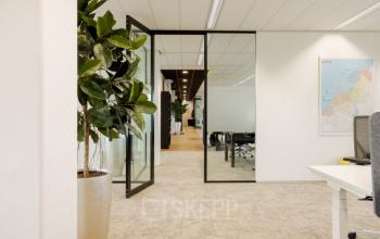 Kantoorruimte te huur aan Zuiderzeelaan 15-25, Zwolle met moderne inrichting en glazen wanden. De ruimte heeft comfortabele stoelen en planten, ideaal voor professioneel werk.