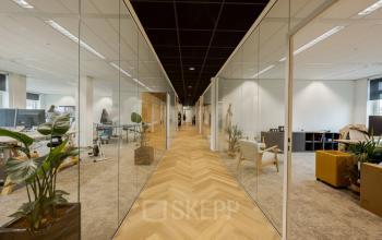 Moderne kantoorruimte huren aan Zuiderzeelaan 15-25 in Zwolle met glazen wanden en stijlvolle inrichting. Medewerkers werken aan bureaus, wat bijdraagt aan een dynamische werkomgeving.