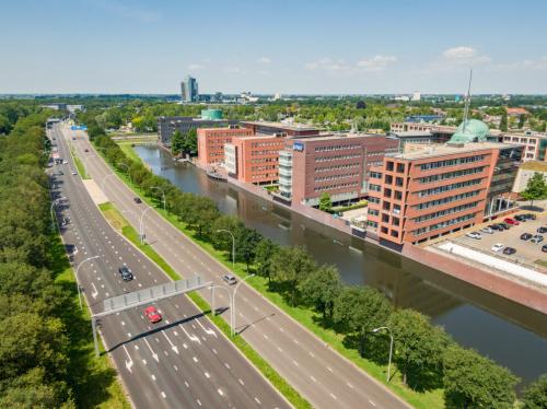 Het exterieur van een kantoorpand aan de Zuiderzeelaan 15-25 in Zwolle, omgeven door een snelweg en een gracht.