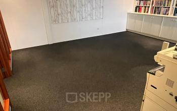 Een ruime kantoorruimte op Pascalweg 6, Zwolle, met een vloerbedekking, boekenplanken en een printer. Ideaal voor wie een kantoorpand wil huren dat klaar is voor gebruik.